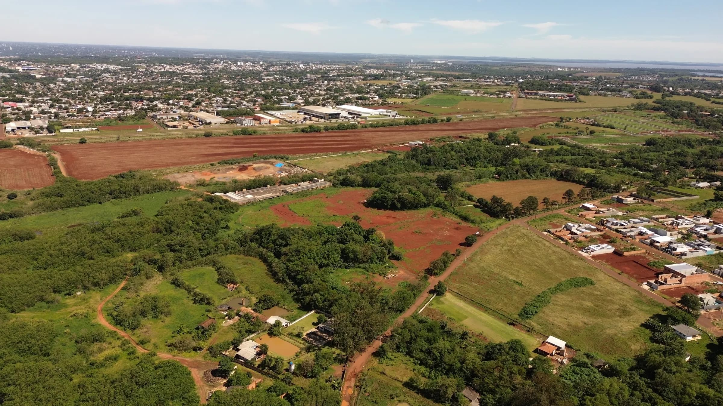 Foto aérea real da área do Loteamento Jardim Isabel com a cidade de Foz do Iguaçu ao fundo, outubro de 2026